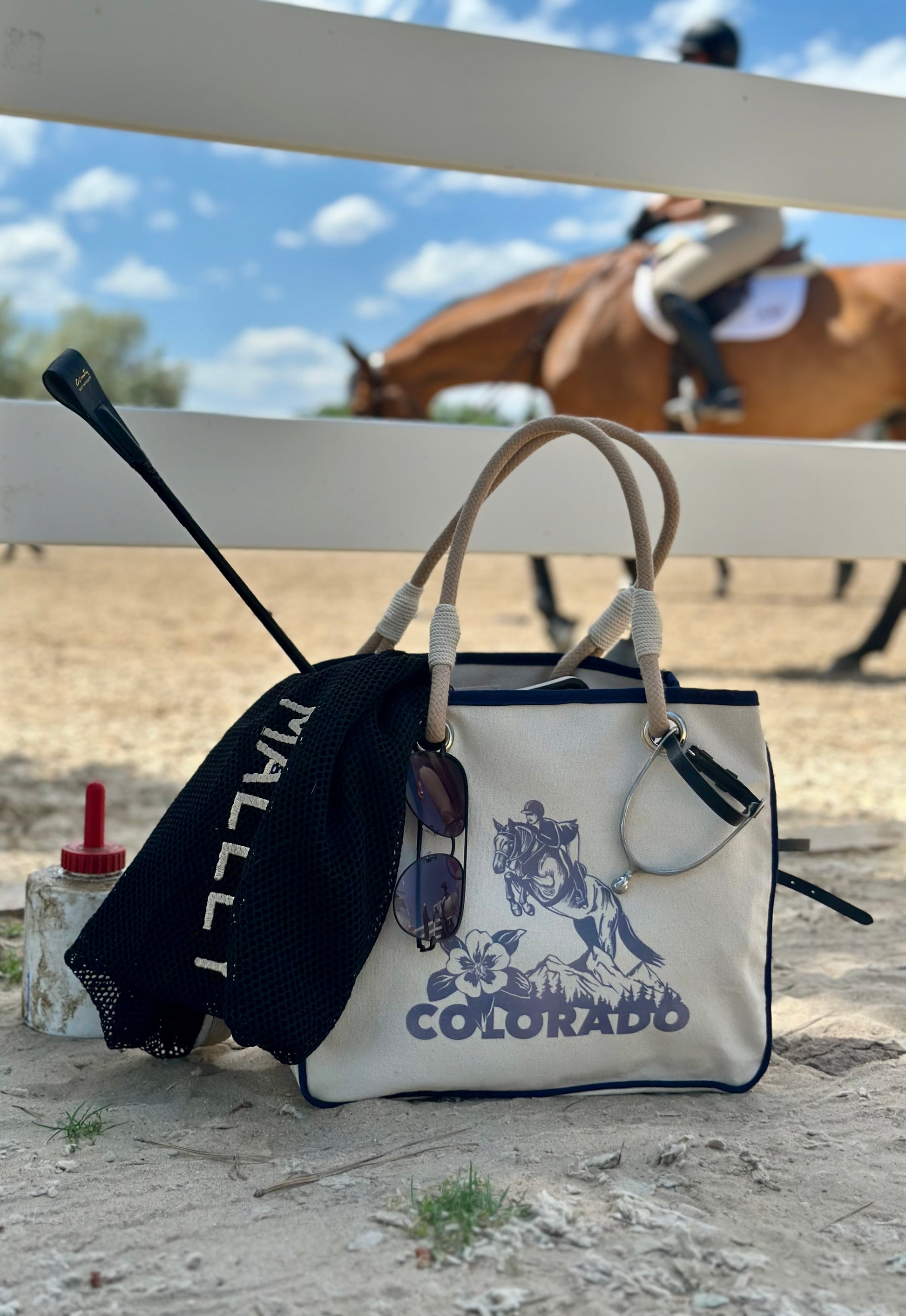 Tote bag with equestrian design and accessories with a hunter/jumper show horse in the background.